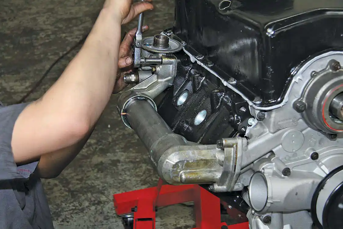 Before rolling the block right side up to build the upper end, the oil cooler/oil filter mount is installed.