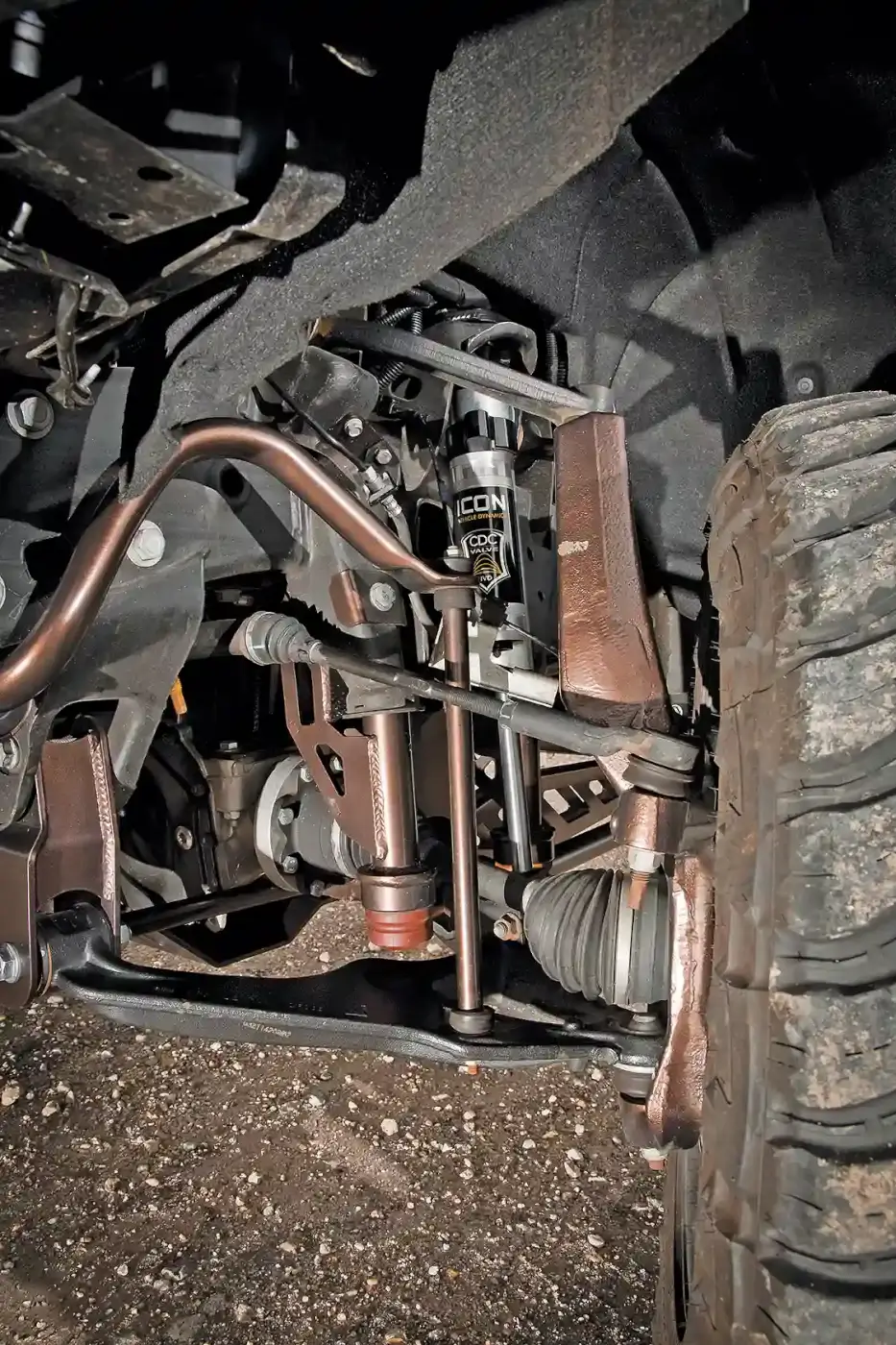 The McGaughys suspension kit is virtually a bolt-on system, No cutting or grinding of the front or rear differential is required, and only a few new holes are drilled. Here you see part of the front suspension. Notice the A-arm lowering bolts, new bump stop extensions, new steering knuckles (spindles) and Icon shocks. All are powder coated to match the body color.
