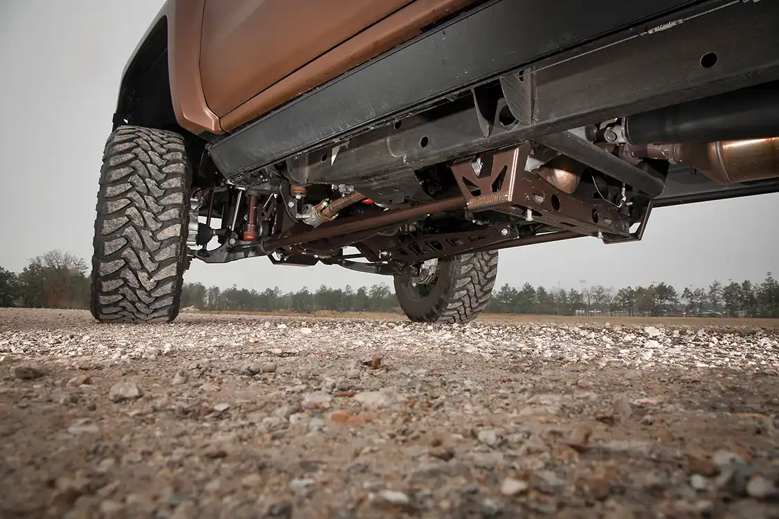 Here you can see the rear half of the McGaughys front suspension. The rear half of the torsion bar mounting is lowered to match the front and the front drop-down brackets are braced at the rear with a custom bracket. Look closely and you’ll see the AMP Research steps tucked up under the doorsill.