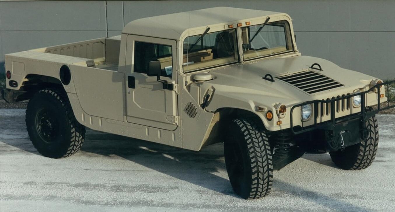 A Hummer H1 in pickup/flatbed two-door configuration. Hummer platforms feature a four-wheel fully independent suspension system complete with heavy-duty springs and hydraulic shock absorbers. Specially designed geared hubs provide a unique gear reduction of 2:1 at each wheel end, doubling the torque output.