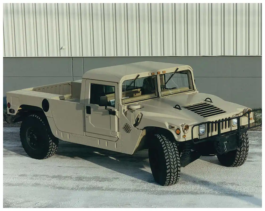A Hummer H1 in pickup/flatbed two-door configuration. Hummer platforms feature a four-wheel fully independent suspension system complete with heavy-duty springs and hydraulic shock absorbers. Specially designed geared hubs provide a unique gear reduction of 2:1 at each wheel end, doubling the torque output.