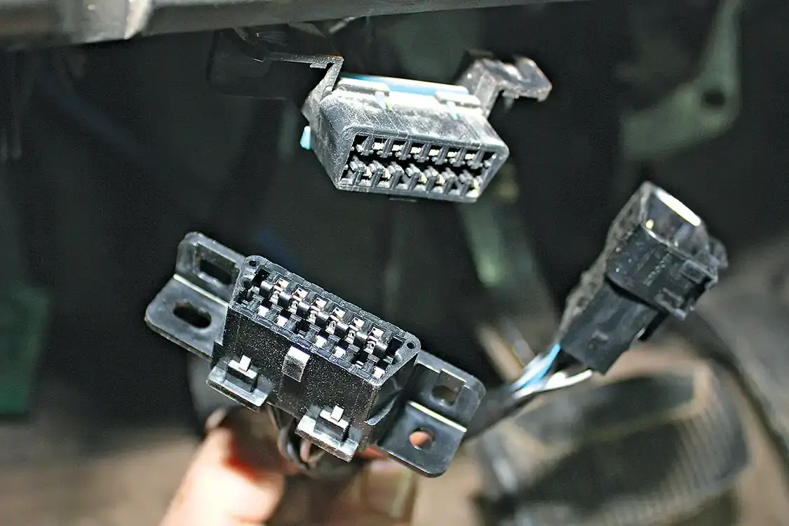 4. The factory OBD-II port will be removed from its mounting location under the dash and plugged into the female end of the OBD-II pigtail in the BD harness. The new male end of the harness will be fastened to the stock location under the dash.