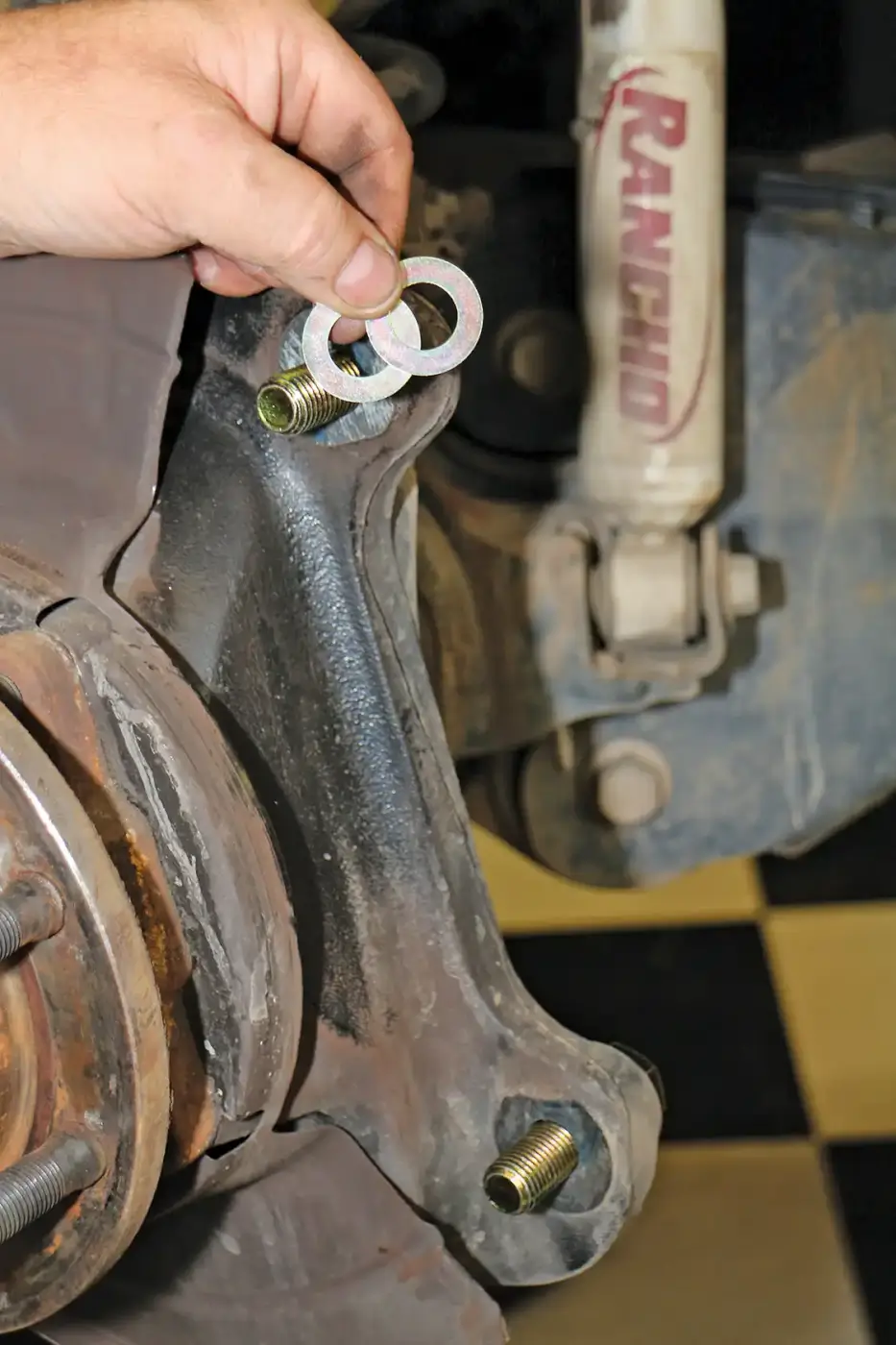 4. Since the Wilwood brake calipers are fixed, these brackets will need to be shimmed to put the rotors in the center of the caliper opening. The shims go between the OEM caliper bracket and the new Wilwood caliper bracket. The bracket and caliper assemblies are test fit until they are on center, as indicated in the kit instructions. A baseline, suggested starting shim pack is listed in the instructions. This will need to be verified with a lock-tit sealer on the bolts before the brackets are bolted down for good. 