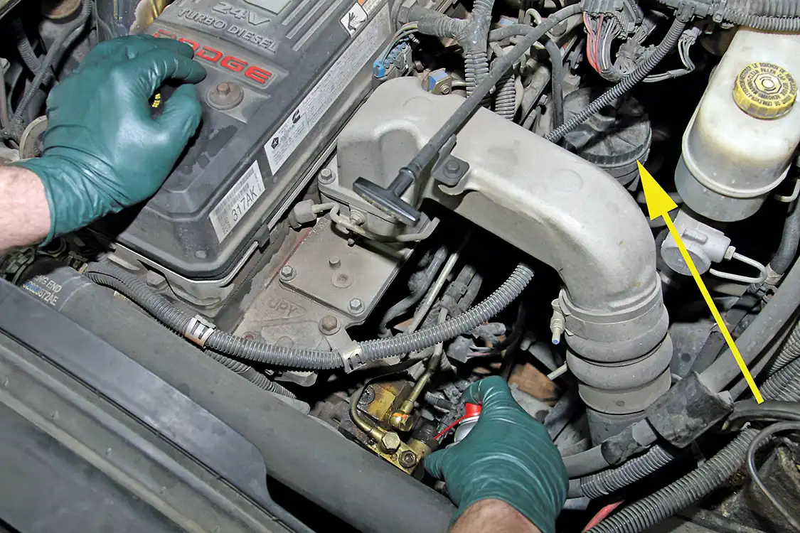 6. Before BDP diesel technician Jack Grubb gets started removing the old CP3, he sprays off the area surrounding the fuel lines with brake cleaner to prevent debris from entering the fuel system. Notice that the factory fuel filter (see arrow) is difficult to get to and messy to change, but that will be replaced by the filter delete.
