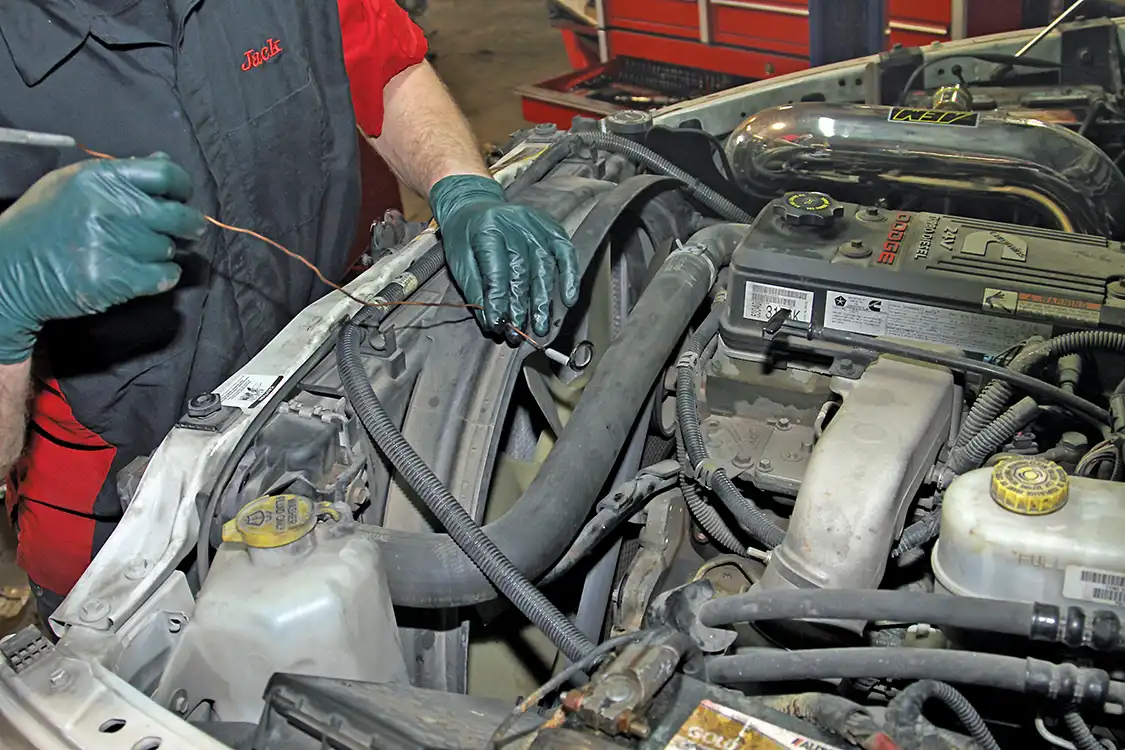 7. Next, Grubb removed the plastic access c over from the front engine cover and loosened the nut securing the gear to the pump. Use extreme care when handling the nut and washer as dropping either down into the front cover would mean a lot more work; the cover would have to be removed to retrieve them. Grubb uses a magnet to make sure the washer does not drop into the cover.