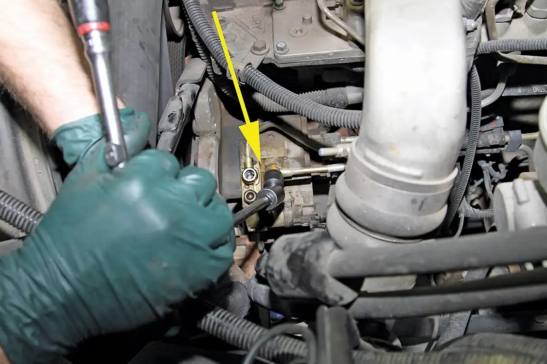 9. Next, he removed the banjo bolts securing the fuel inlet and return lines to the CP3 pump housing (see arrow). This was followed by unplugging the pump control harness, then removing the output line between the CP3 and the fuel rail.