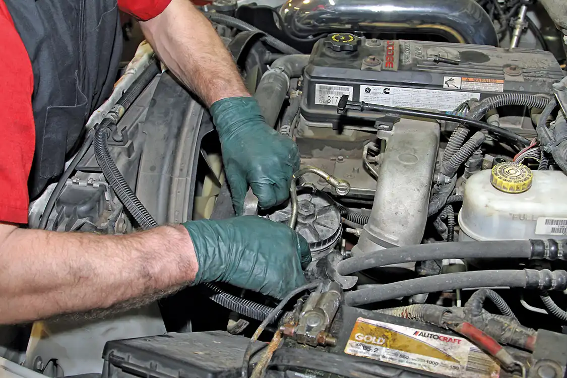 13. Next, the factory fuel filter assembly was removed. First, the fuel heater and Water in Fuel sensors were unplugged. Grubb then removed the banjo bolt from the front side of the filter housing as well as another banjo fitting on the rear side. The entire assembly could then be slid forward and discarded.