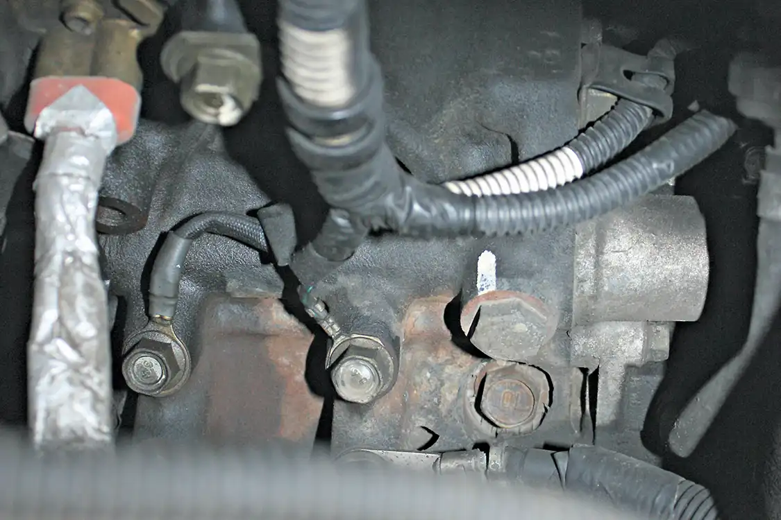 9. To feed oil to that new turbocharger, the large plug (next to the white mark) on the front passenger side of the engine will be removed and replaced by an AN-style fitting. A stainless braided line will then be routed from this new oil gallery port to the turbocharger oil inlet. the factory turbocharger oil feed is located in the valley of the engine and fed off of a camshaft journal; the port is small and unreliable when trying to keep an aftermarket turbocharger fed.