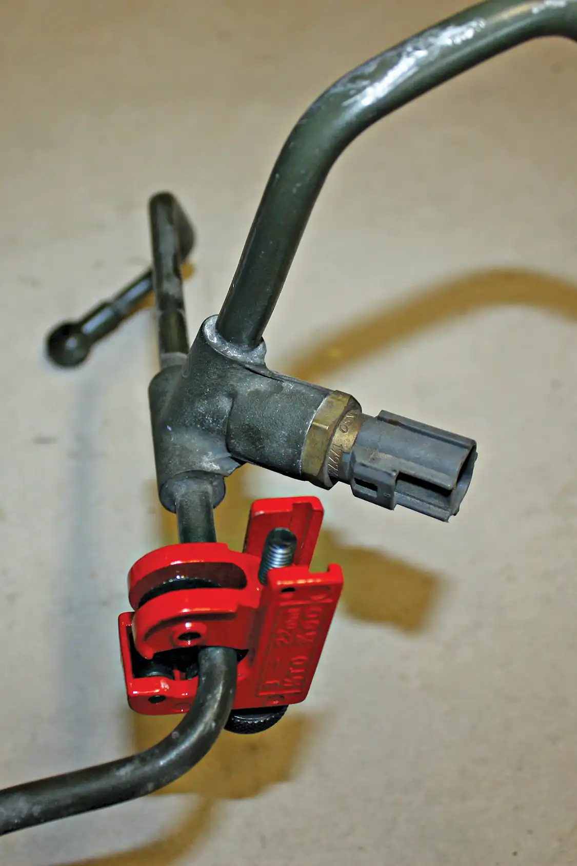 3. The stock return line needs to be cut in two places; a small pipe cutter will make short work of it and allow the two sections to be reinstalled, connected with supplied rubber hose and brass barbed tea-routed inside the valley of the engine for better clearance around the new Y-bridge.