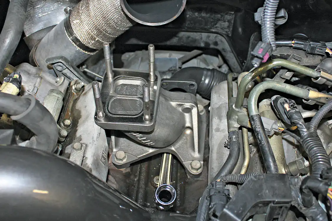 7. The HT Turbo T4 pedestal is then installed into the factory turbocharger mounting location using the original bolts. The 5-inch-tall pedestal allows the use of an HSP billet-machined riser block to raise the S300 turbo even further out of the valley, while running the S300 as a single shouldn't require a wastegate, the riser block can be purchased with an optional external wastegate port. You can also see the supplied stainless braided oil drain line that routes oil back into the stock location under the pedestal.