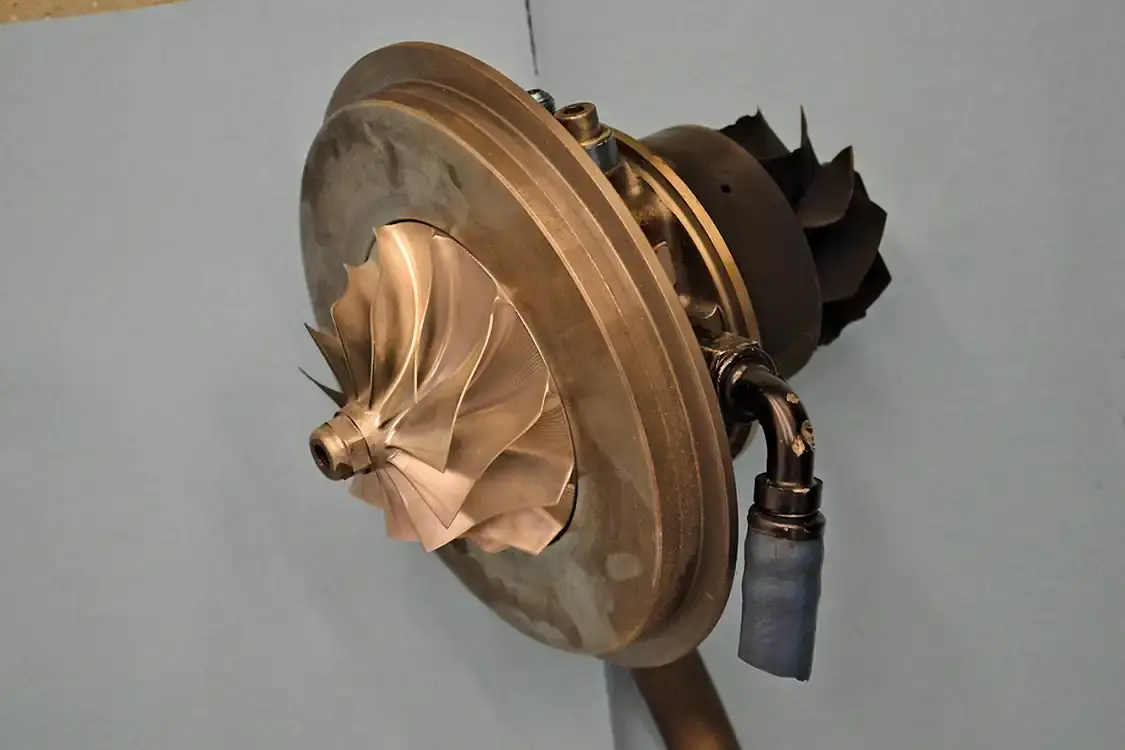 With the compressor and exhaust housings off this Garrett turbocharger, you can more clearly see the compressor wheel (left), the turbine (right), and the center section (middle), which in this case is a high-performance ball-bearing unit.