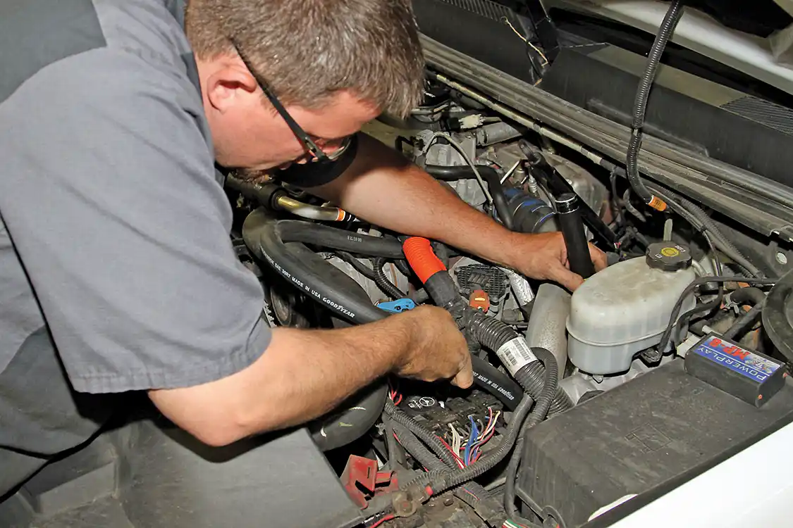 18. With the hose secured at the fitting end, carefully route the hose to loop up and then over and down to the frame rail on the driver’s side of the engine. Be careful not to route the hose near moving and/or hot items when operating the truck.
