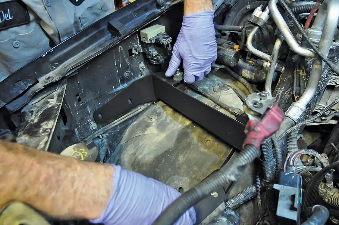 20. After removing the battery, battery tray, and factory vacuum canister, Wamsley bolted this bracket that the new oil cooler assembly would mount to. It’s rubber mounted to eliminate any noise transferred from the engine to the cab.