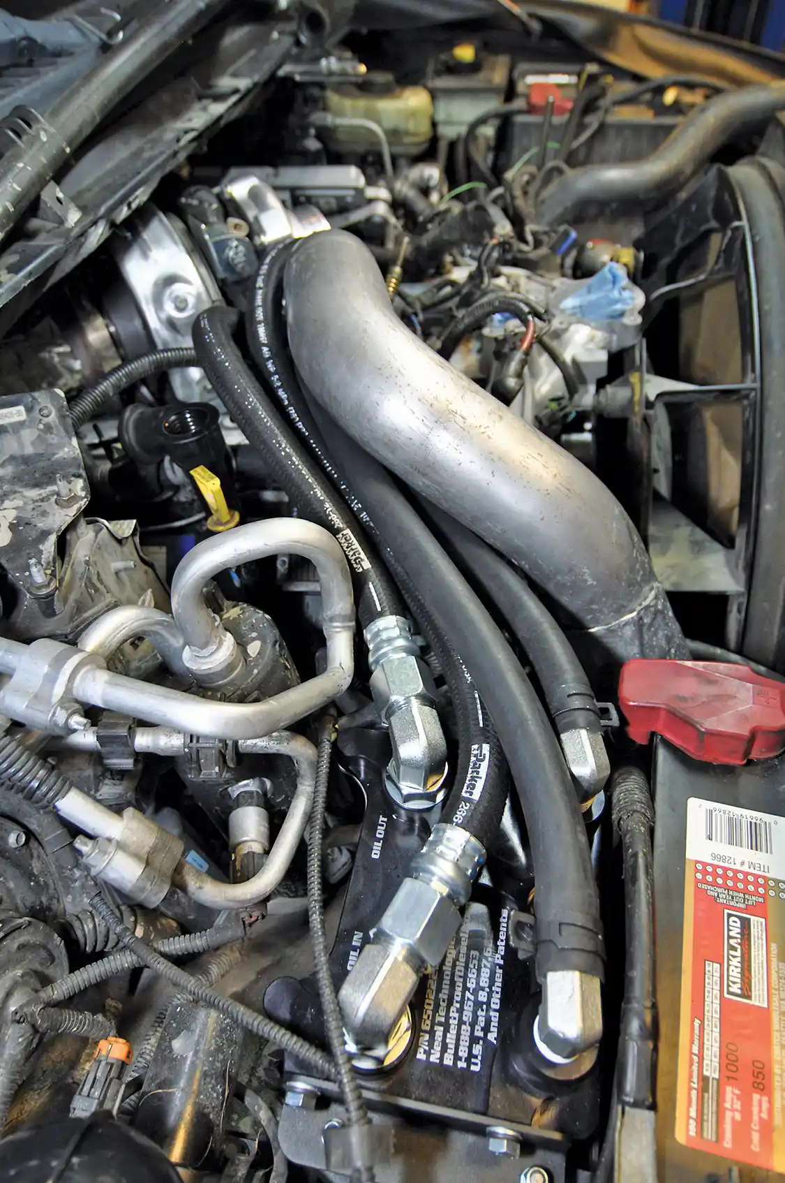 25/26. Next step: Wamsley ran all four lines (oil feed, oil return, coolant feed, and coolant return) across the engine to the new oil cooler assembly. The oil fittings were snugly tightened and aligned; then the jam nut was tightened to ensure a good leak-free seal. Coolant fittings connect via push-on fittings and a pair of spring clamps just like Ford uses.
