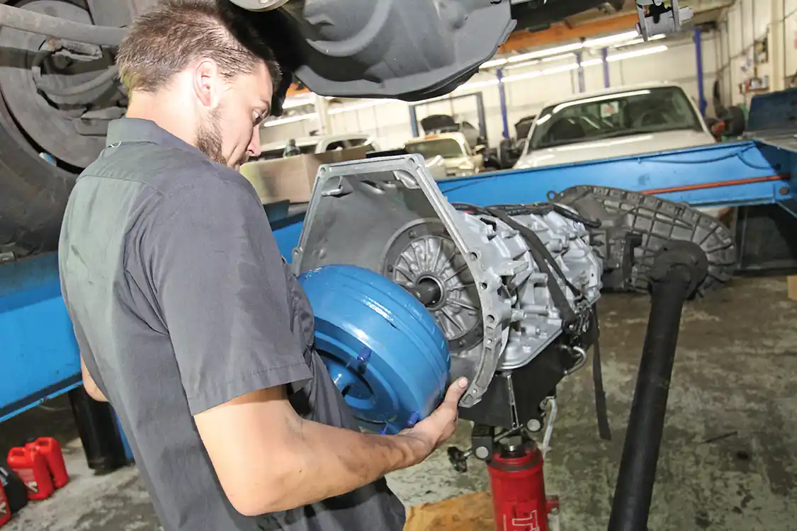 9. The torque converter, after checking that it is full of fluid, is installed on the transmission input shaft. Look closely and you’ll also see that the front driveshaft is bolted to the T-case, before installing the unit in the truck. This is said to be easier than bolting to the front output while in the truck.