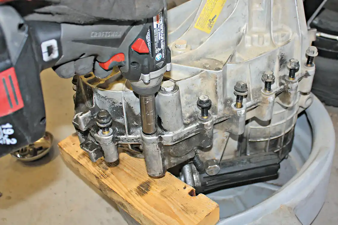 13. With the rear snap ring and the rear shaft disengaged, the outer case bolts can be removed. The use of a cordless impact or air impact is going to come in handy here as these bolts are snug and will have some sealant on them, so they won’t come out easy by hand. Take note of which bolts have brackets attached to them as they’ll have to go back in the same place.
