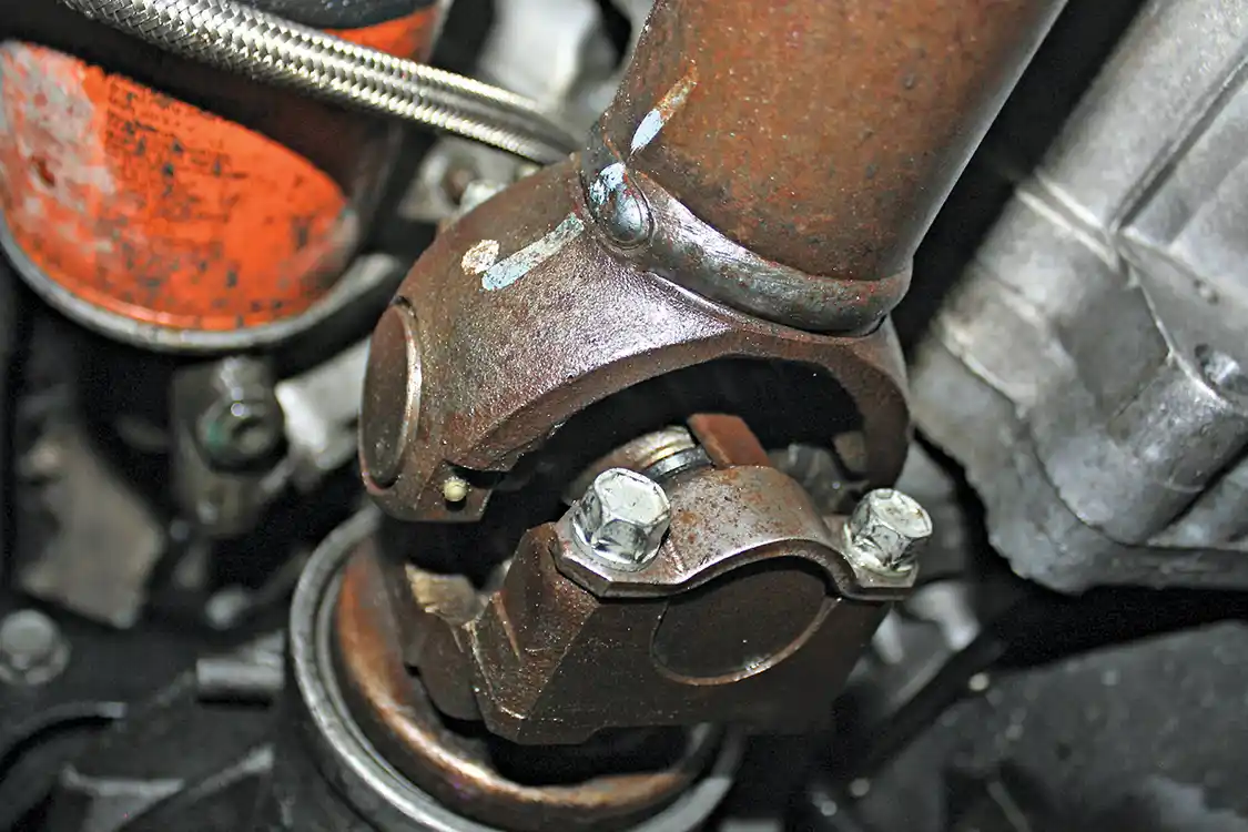 3. With the case drained you can then remove the front and rear drive shafts. Both shafts use slip joints at the transfer case, but two straps held in with bolts will need to be removed on the axle side. A pry bar will help bump the u-joint out of the pinion. If your u-joints have any noticeable play or a lot of miles on them, now may be the right time to change them out with new units.
