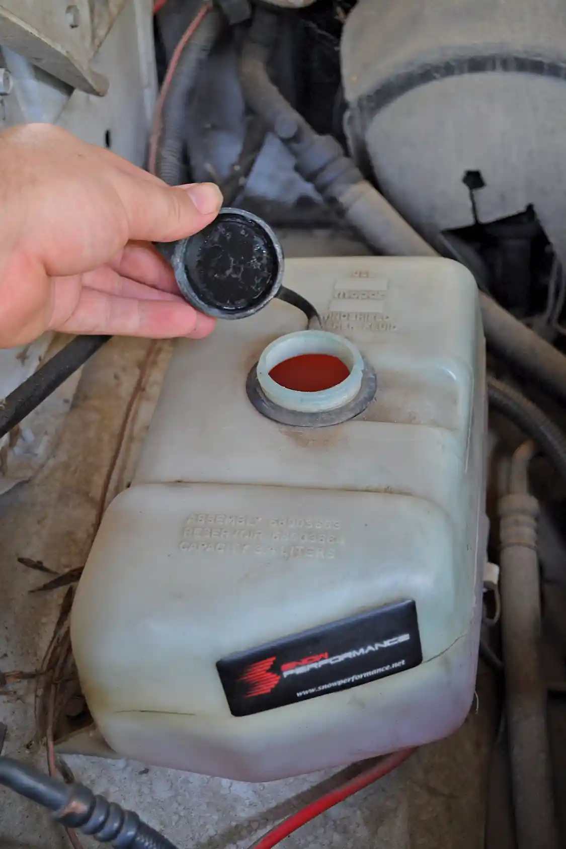 3. If you're just looking for an extra burst of power and don't need much capacity, a stock windshield washer reservoir can be used as a water-methanol tank. The red fluid inside is Boost Juice, a 50/50 pre-mix from <a href="https://www.nitrousexpress.com/">Snow Performance</a>.