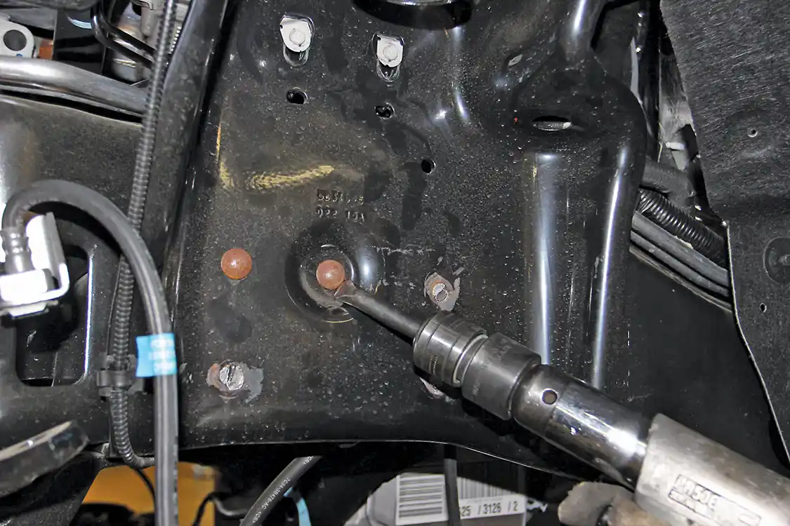 2. Installation at the front begins with raising the truck and then removing the stock components. Here you see the front upper coil bucket and shock mount brackets being removed. The OEM rivets must be cut off; an air chisel works best for this.