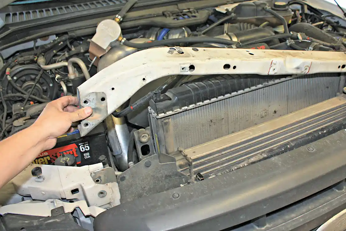 4. With the brackets and hardware removed, four 13mm bolts on the front and back of each side of the core support are removed, so it can be slipped up and out of its location. A pry bar may be needed to slide the core support out.