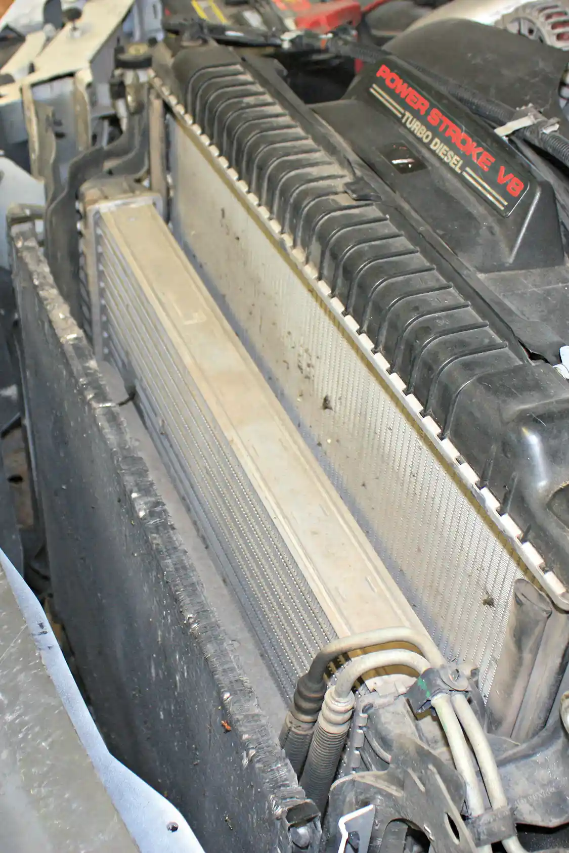5. With the upper support out of the way, you get your first good glimpse of the stock intercooler located there between the A/C condenser and radiator. Before it can be removed, the driver and passenger side intercooler pipes are going to be unclamped and slipped out.
