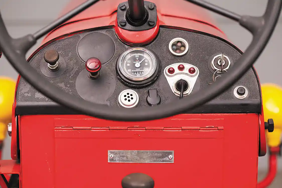 Like many ‘50s tractors, the dash is typically austere. The horn and turn signal add to the complexity. If the hour meter is original, this tractor only had 4,058 hours at the time of sale. The hinged cover below is a storage compartment.