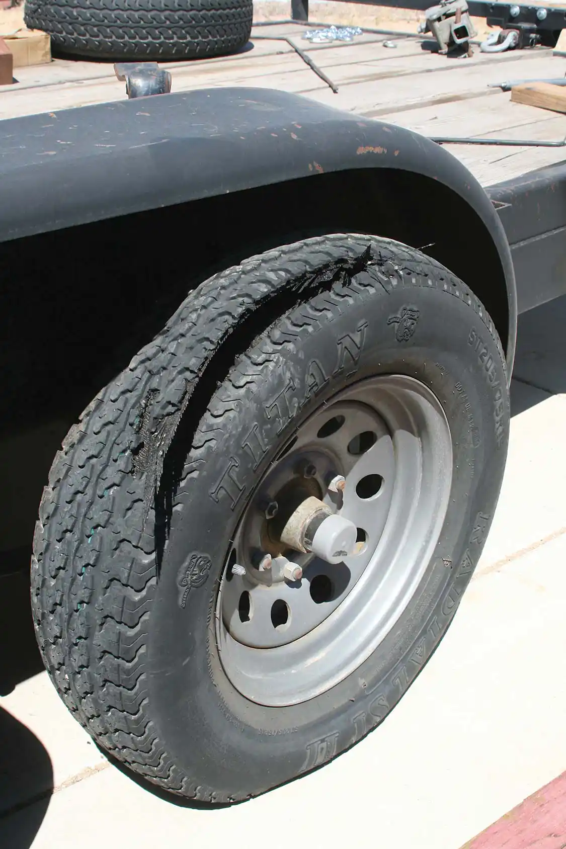 Even though this trailer tire was showing good pressure and a nice deep tread, it failed. Most likely this was due to the fact that the tire date code showed it was over 10 years old, and had deteriorated internally. This tire failure caused additional damage to the trailer fenders that wouldn’t even allow the spare to be run, without some roadside blacksmith work on the bent fender. A simple check of dated codes would have encouraged the owner to replace the aged tires on this trailer. Any tire retailer can do tire date code readings, or you can do it yourself.