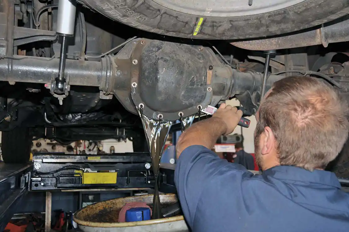 2. Cory LaBouve at B&amp;C Auto Repair in Vista, California, got to work on the truck. First, he removed the bolts securing the stock rear differential cover. And then used a scraper to get the cover loose. One of the disadvantages of the factory pan is there’s no drain plug. The PML pan not only has a drain plug but it also has a level plug (when oil runs out it’s full) and, of course, a filler plug.