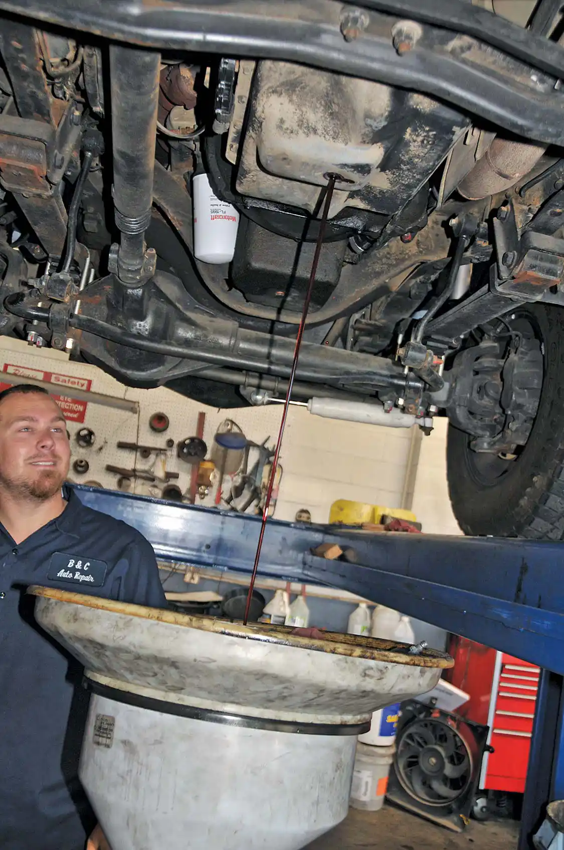 6. The transmission oil pan was the next target on the list of things to do. First, the oil was drained from the pan. Then, Cory removed all the pan bolts. The factory pan was removed and drained into a recycling container.