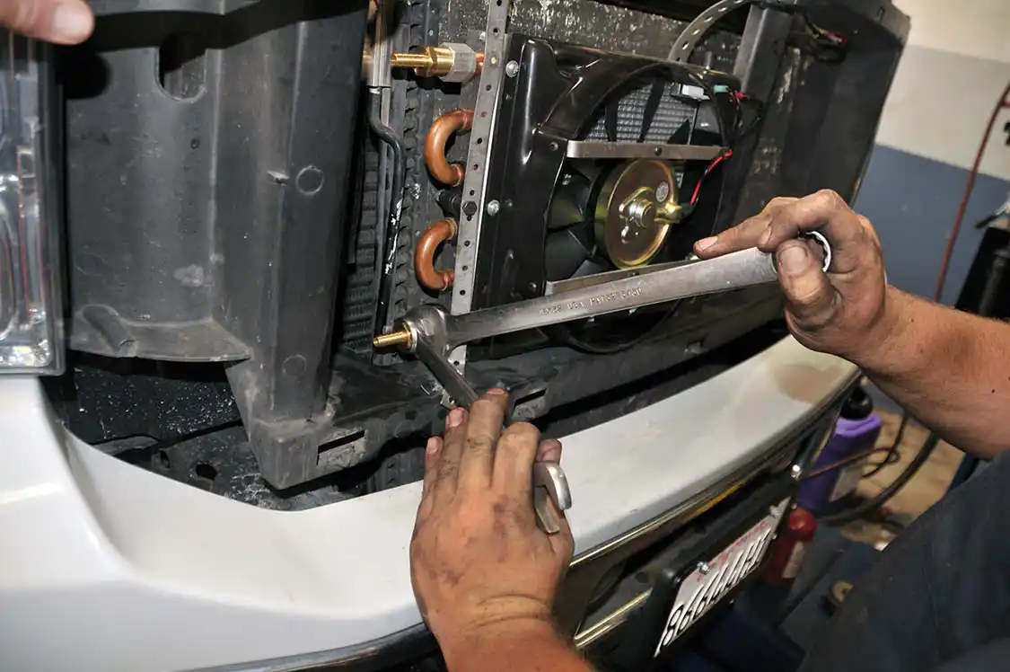 17. Two barbed fittings were used to tie the cooler into the existing system. Here Cory cinches down the fittings, making sure to use pipe thread sealant to help prevent leaks.