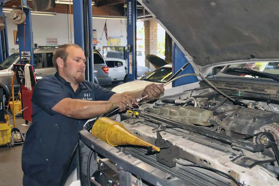 24. Cory added a hose to his oil-filling machine to reach all the way to the back of the engine compartment where the transmission filler tube is located.