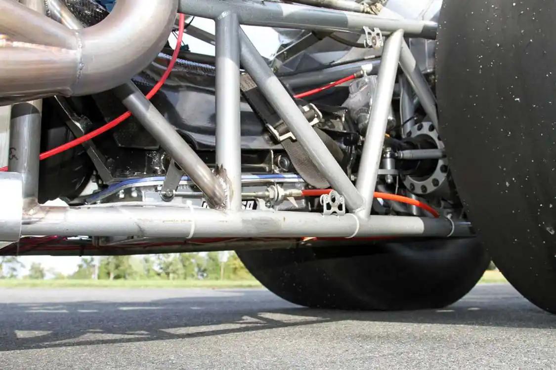 Peaking under the chassis between the headers and the rear tires you can see the <a href="http://www.rosslertrans.com/">Rossler</a> Turbo 400 transmission along with the <a href="https://csr-performance.com/shop/department.da/flexplate-shields">CSR</a> scatter shield and <a href="https://protorque.com/">ProTorque</a> torque converter.