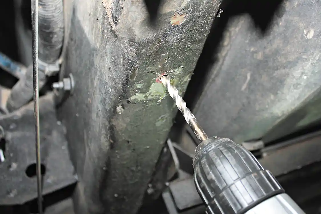 11. Setting the bracket and bar aside, the previously marked location on the frame can then be drilled, first with a ¼-inch bit, then finished with a larger ½-inch bit. Only one hole needs to be drilled at this time, as the bracket can then be installed and bolted into place.
