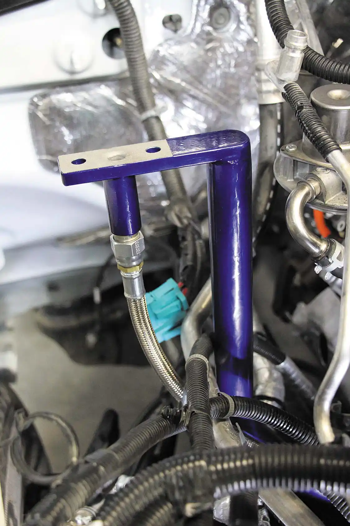 19. With the injectors and CP3 installed, the guys at Randall’s started installing the compound turbo system. A nice feature in all Wehrli Custom Fabrication twin kits is that the atmospheric turbo pedestal incorporates the oil drain fitting into the bracket itself (shown). This eases the oil drain line installation after the turbo has been mounted, and also eliminates a leak point. High-quality Parker braided stainless steel oil drain and feed lines with stainless ends come standard in the Wehrli twin kit as well.