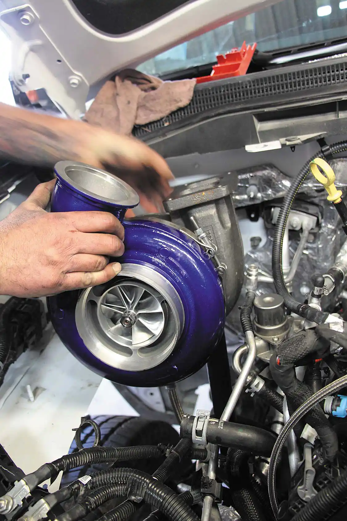 20. Although the placement of the atmosphere turbo forces it to be moved forward, retention of the passenger side battery under the hood is something that’s unique to Wehrli Custom Fabrication’s LML Duramax twin kit. The factory coolant bottle is done away with for space reasons, but a fabricated aluminum tank (complete with low coolant sensor) is supplied in the Wehrli kit.