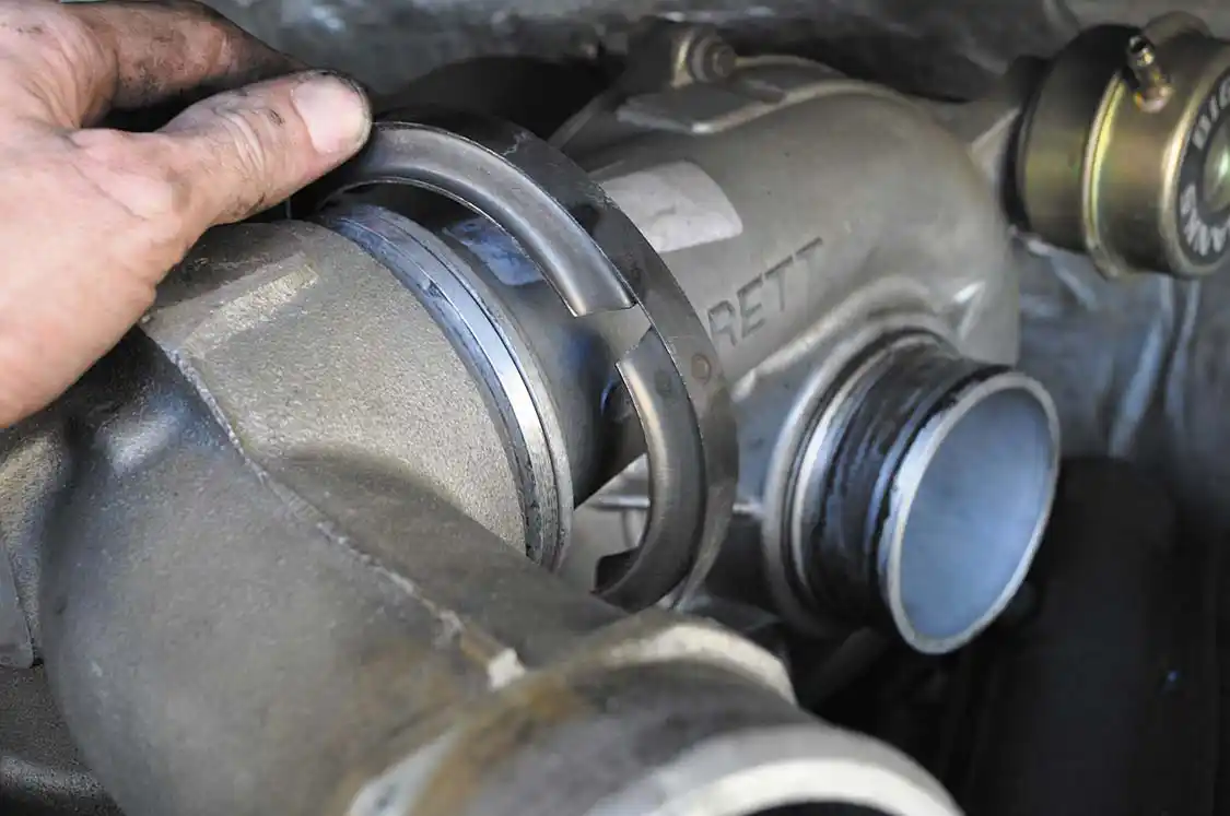 13. The Garrett GT38 turbo uses a V-band clamping setup on all positive pressure ports. This one seals the pressurized air coming from the turbo to the intake spyder and later going to the intercooler. Removal requires loosening the clamp and popping the individual pieces of the clamp free with a small pry bar.
