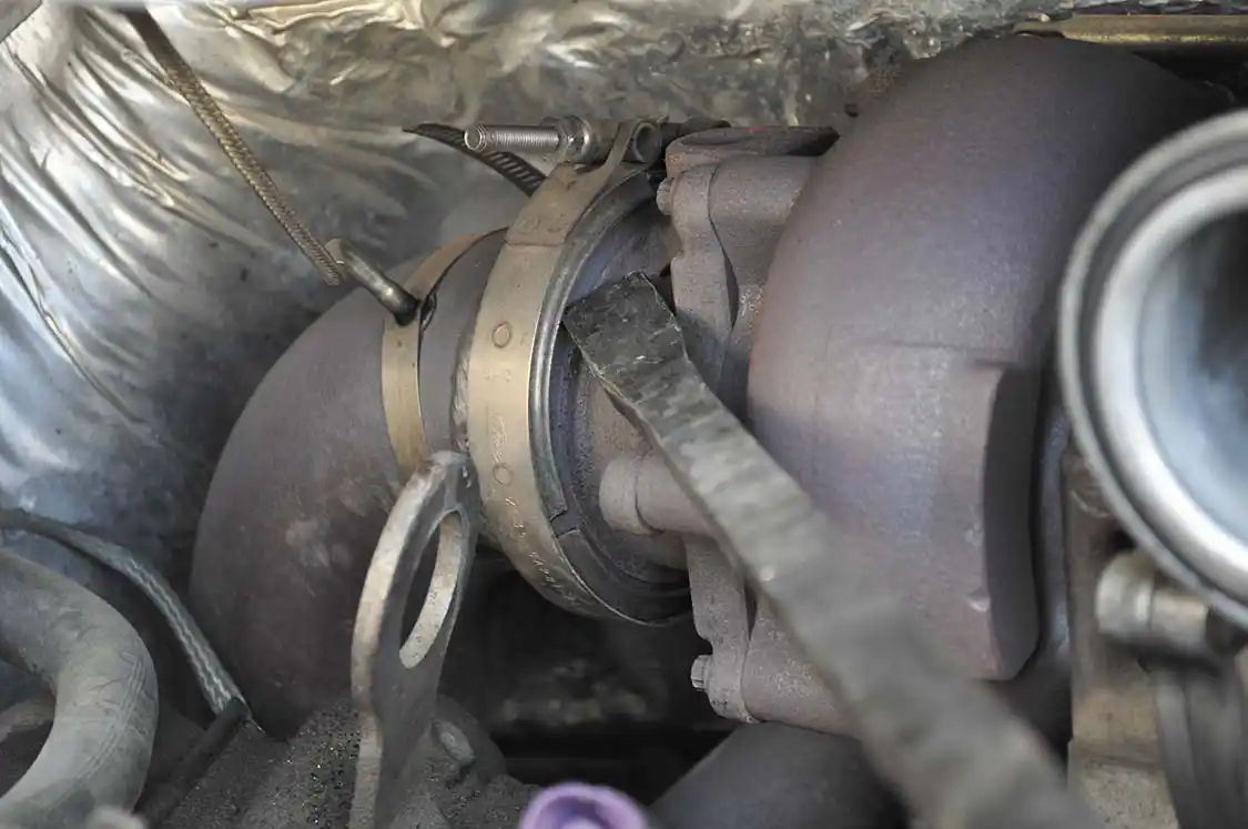 17. At this point two V-band clamps on each exhaust port and a pair of bolts are all that secure the Garrett Turbo to the 7.3. Removing the downpipe clamp was fairly simple. We loosened the clamp and popped each steel V-band piece free with a pry bar. The clamp on the back side is another story. It’s a huge pain to access. We ended up using multiple prying “instruments” and a 3-lb sledgehammer.