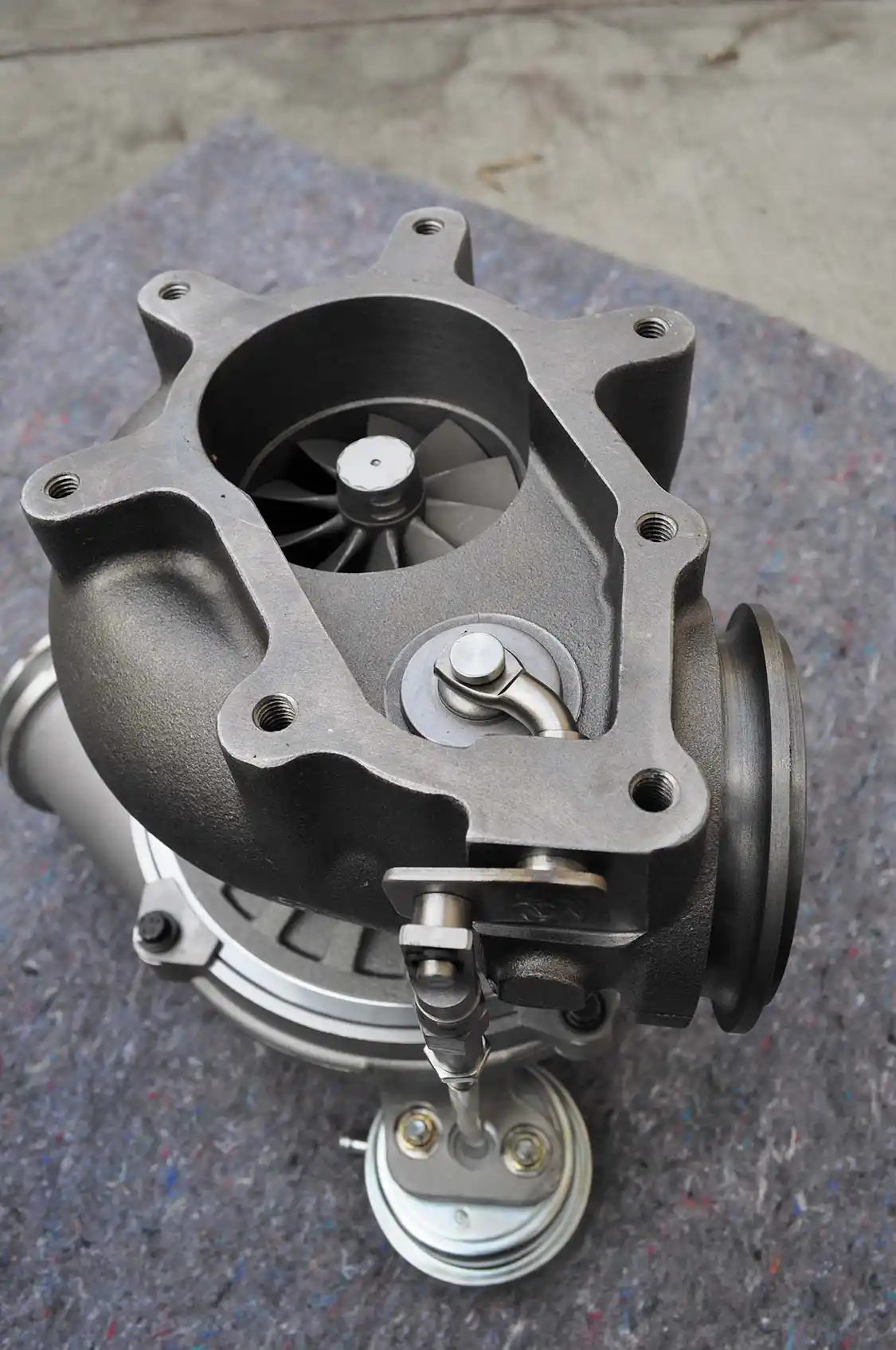 23. With the turbine outlet flange off the new Turbo Thruster II we can see the wastegate. During rapid defueling, such as gear changes, this gate opens diverting exhaust pressure (a.k.a. “drive pressure”) away from the turbine and out to the down pipe. This helps save the turbo from damage when boost air is not needed by the engine.