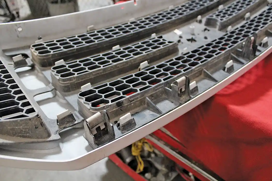 3. Here’s a closer look at the clips that hold the base of the grille in place. They’re stubborn but they should pop out with a little pressure. Corder’s method is to pull the upper portion of the grille out and then use a long pry bar behind the grille to “help” the clips out of their homes in the core support.