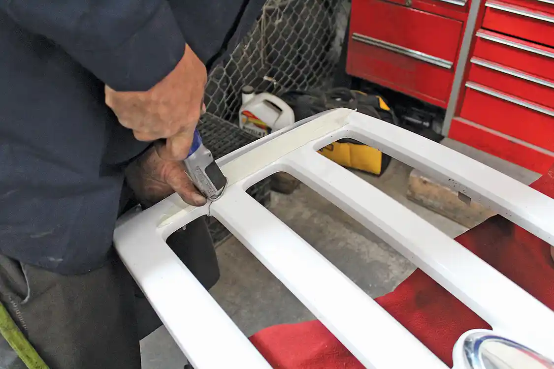 6. With the grille pieces separated, it’s time to break out the cutting tools and do some trimming. For this installation, the two center slats must be removed from the grille shell. Corder applies masking tape to protect the paint, then uses a small body saw to do the necessary trimming. A hacksaw could also be used, though the cut won’t be as quick or as clean. The shell is too thick to cut with a sharp knife.
