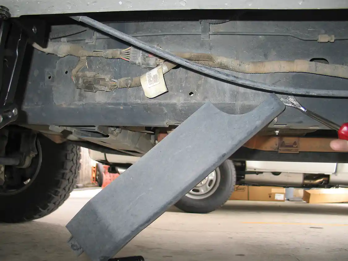 2. On the frame rail under the driver’s door is a factory wire harness cover, attached by two large tree clips. The thickness of the factory cover interferes with the motion of the PowerBoards linkage arm, so it will be replaced by a part in the kit.