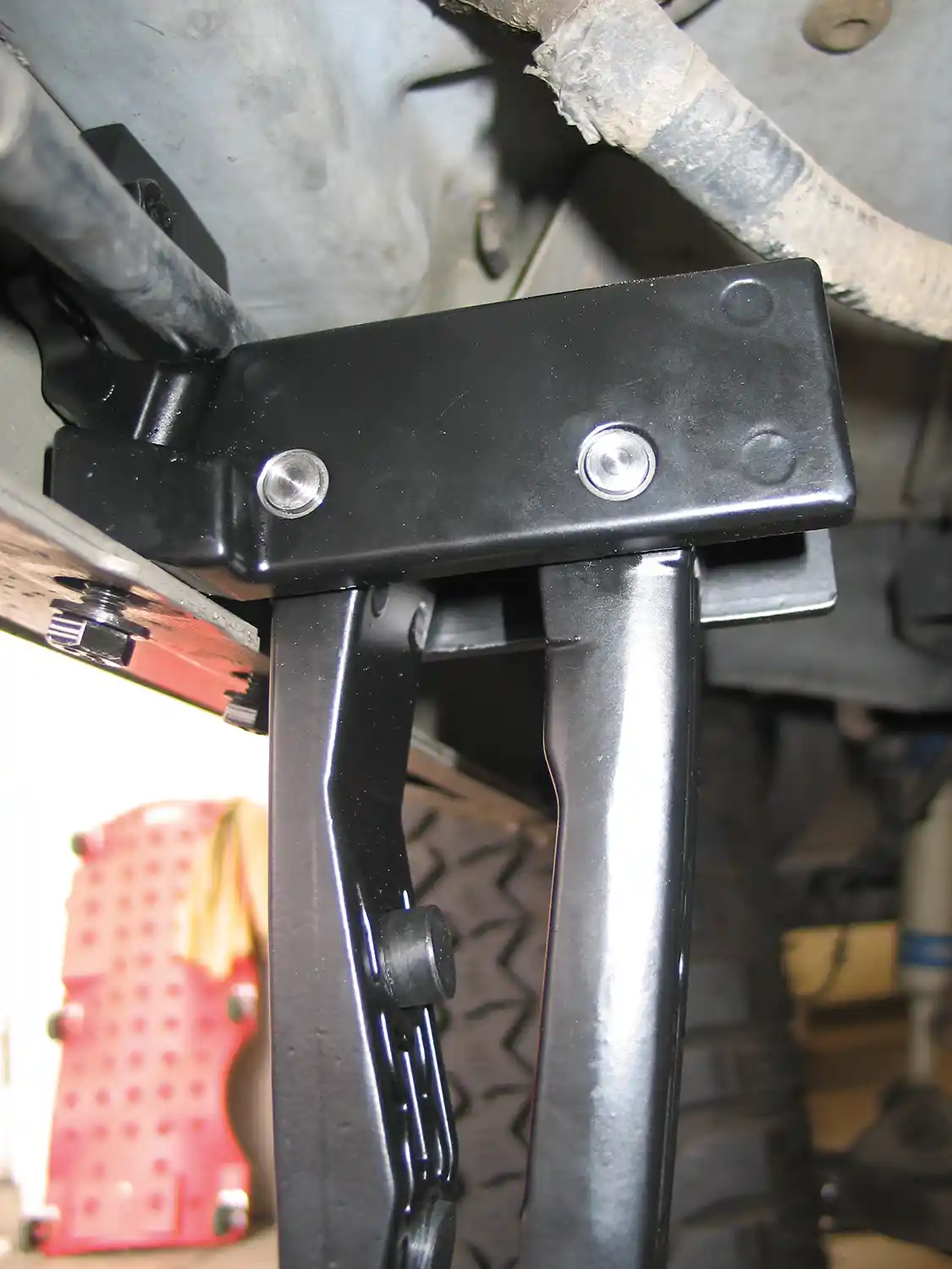 3. There are two different linkage arms: two with a cog and connection point for the motor and two without. The two without attach at the front of the truck in two locations, under the small hex bolts from step one, and with the addition of two more small bolts that go through the rocker panel. Again, the bolts are left finger-tight.