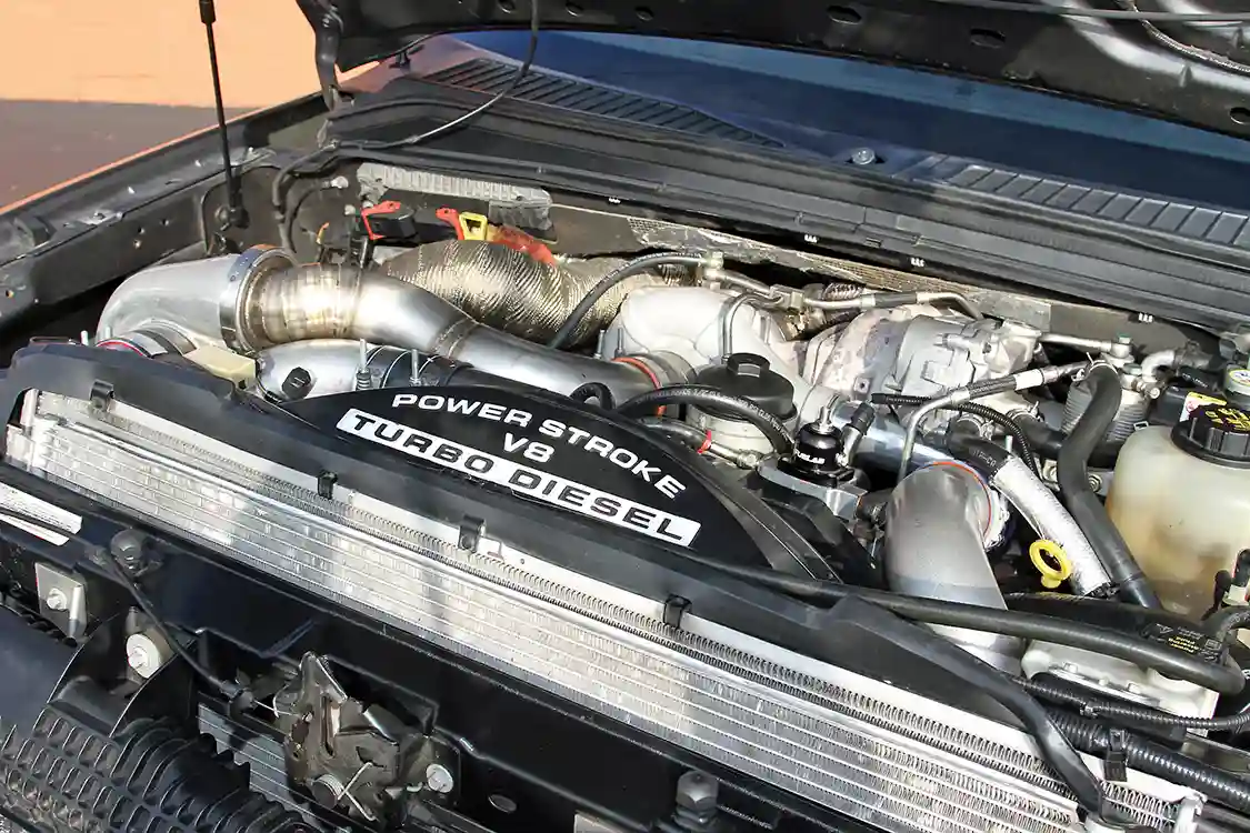 Lifting the hood on this F-250 reveals that the factory compound turbo setup has been supplemented with a large <a href="https://www.borgwarner.com/home">BorgWarner</a> turbo.