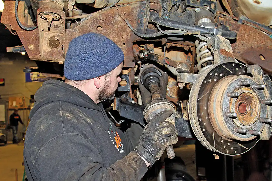 2. He then unbolts the inner CV joint from the differential and removes the complete CV axle assembly as one unit.