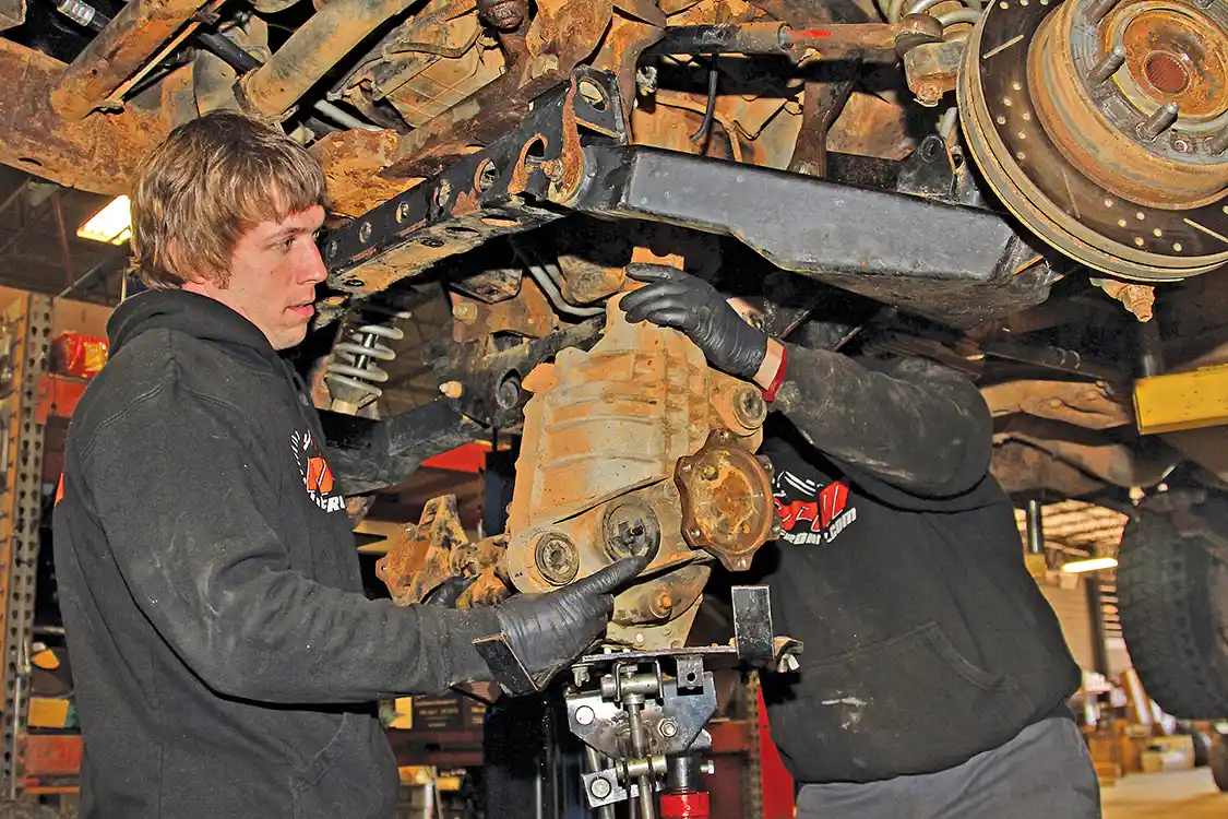 5. Next, Michael Powell helps steady the differential assembly while Nelson lowers it out of the truck using a transmission jack. A couple of strong friends can substitute for a trans jack in a pinch.