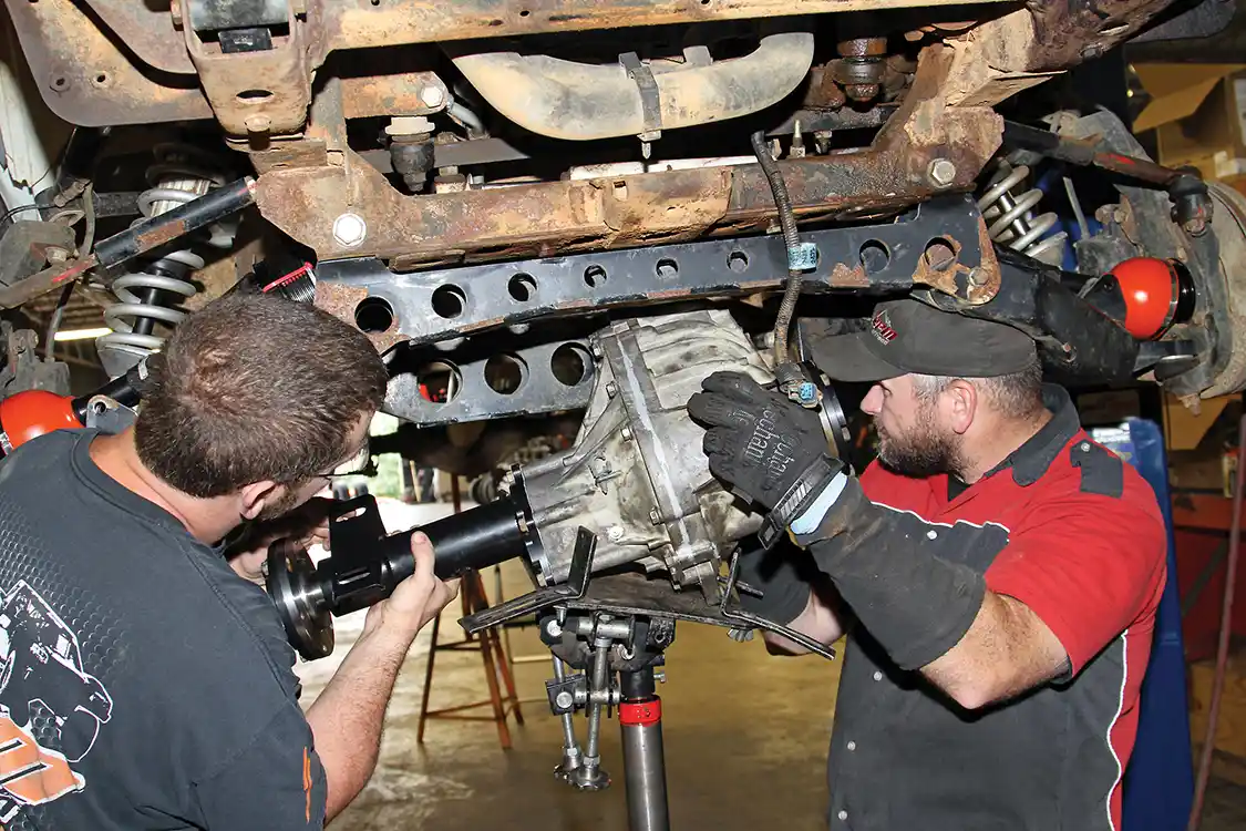 26. Kevin Schurtz helps steady the upgraded AAM axle assembly while Nelson lifts it into the truck with the transmission jack.