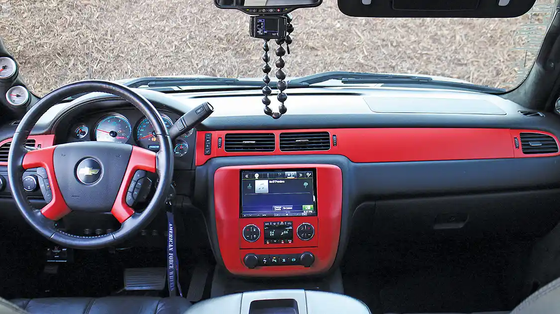 The crew cab factory interior was left unmolested. The crew at Lucky 7 wrapped the dash, door panel inserts and steering wheel spokes in contrasting matte red vinyl. Road trip travelin’ tunes are produced by an Alpine DVD head unit/monitor powered by an Audison AV 5/1k amp located under the rear seats. Four Hertz Nertz speakers were installed in the door panels, while two Hertz Nertz 10-inch subwoofers are hidden underneath the rear seats.
