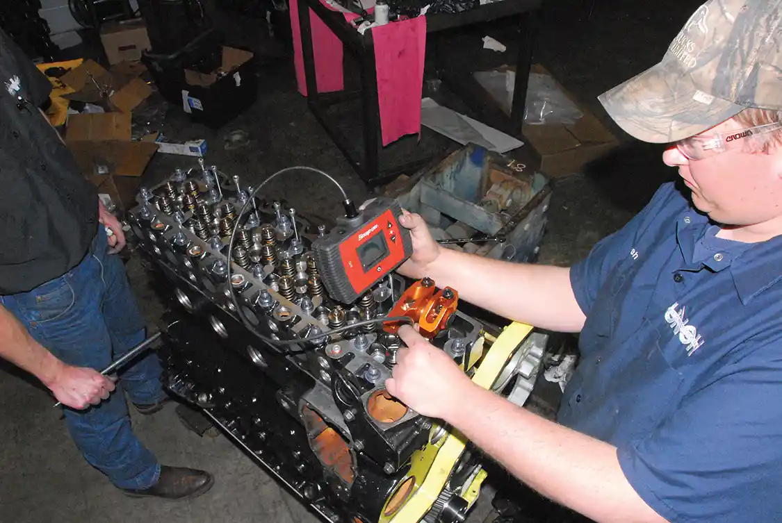 9. They said it couldn’t be done—namely combining the high-lift Hamilton cam with the <a href="http://harlandsharp.com/">Harland Sharp</a> high-ratio (0.050” lift) rockers. Here valve-to-piston clearance is being checked with a bore scope. With the thick head gasket and flycut pistons there was enough clearance, but the problems were found with valve spring and rocker geometry. While the engine made some runs like this, it was ultimately decided to go back to the stock ratio rockers. “They” were right.