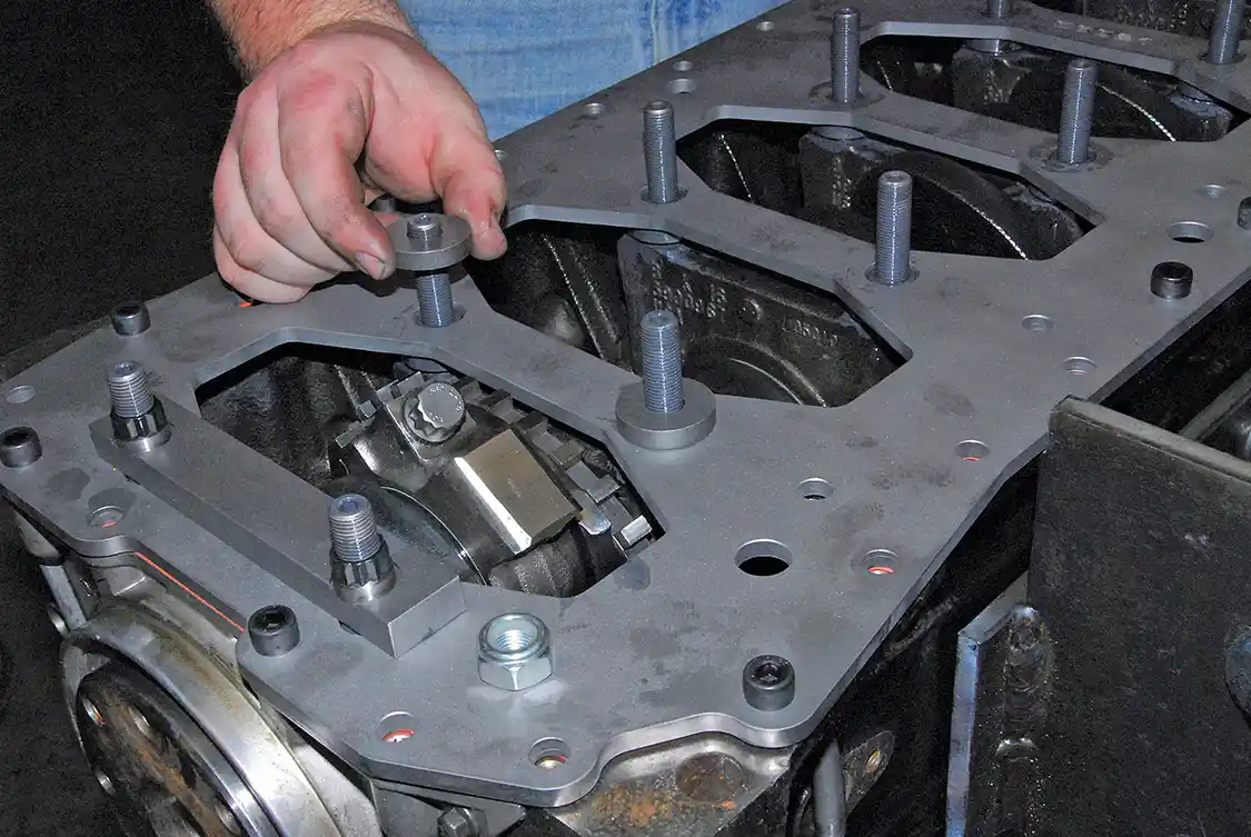 17. More spacers go over the studs followed by hardened washers and nuts. The spacer block goes over the rear main cap and uses special 12-point nuts. Install the Nyloc nuts in the kit and torque all bolts to 120 ft-lb. Turn the crankshaft to make sure nothing hits or binds. Next steps are to install the oil pickup tube, spacer and gaskets, as well as the oil pan.