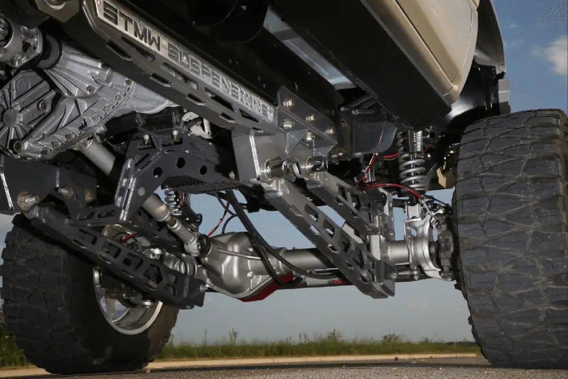 The four-link kit was custom-built by ShowTime Metal Works. The Naivars had a Ford transfer case custom-machined to fit the Allison transmission. It was an expensive upgrade, but the driveshaft sits at a factory angle and won't bind at any suspension angle, from full compression to full extension.